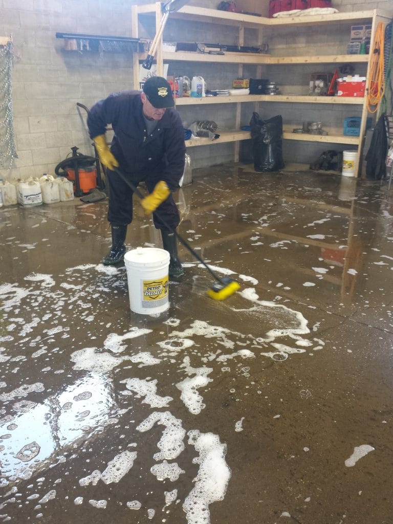 Mechanic shop owner removing oil from shop floors with Petro Buster